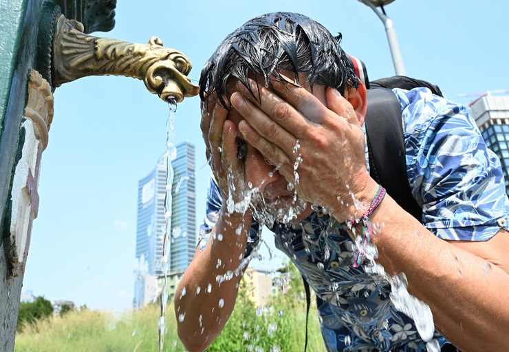 Uomo si rinfresca sotto una fontana