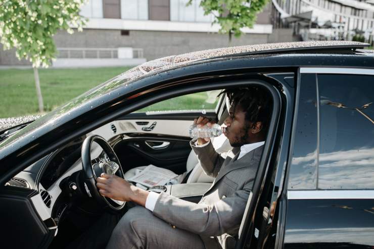 Uomo beve acqua in auto