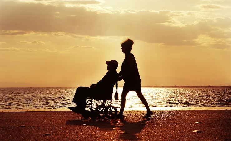 Persona disabile sulla spiaggia con un'accompagnatrice